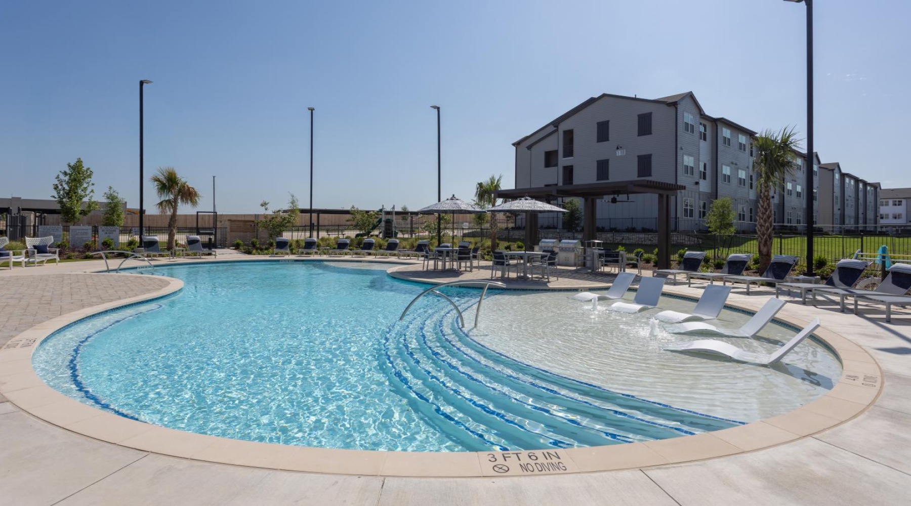 a pool with lounge chairs around it and a building in the background
