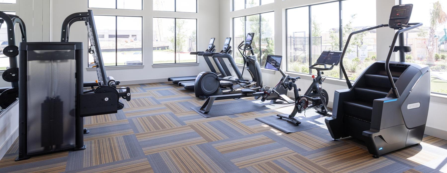 a gym with treadmills and windows