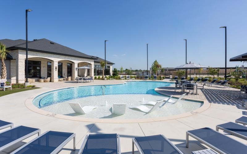 a swimming pool outside a building with lounge chairs