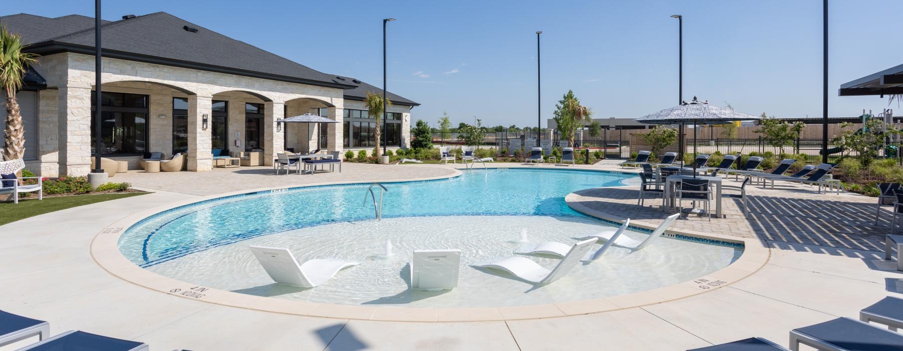 a swimming pool outside a building with lounge chairs